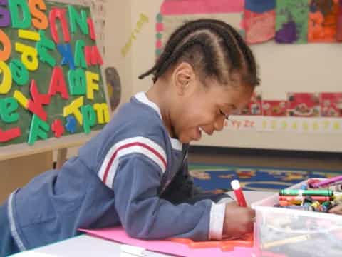 a young boy coloring on a paper