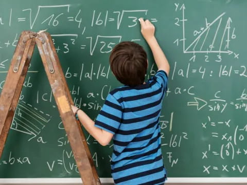 a boy writing on a chalkboard