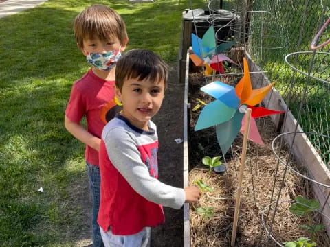 two boys standing next to a fence