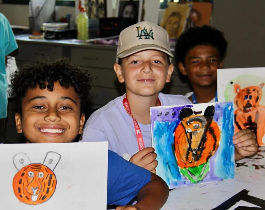 a group of boys holding up drawings