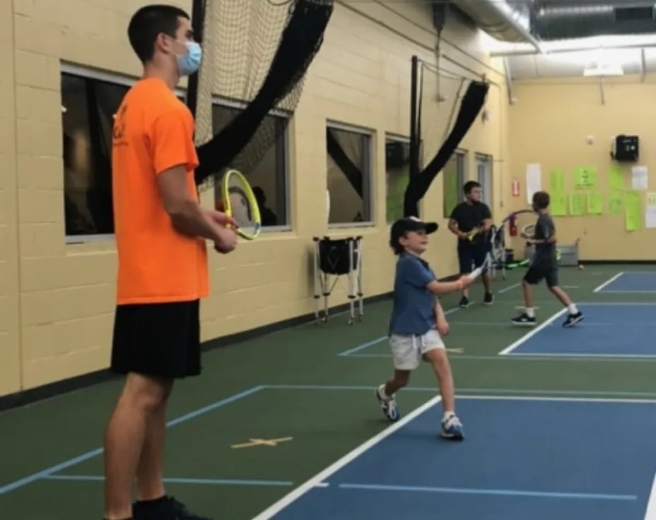 a person and a boy playing tennis