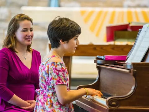 a woman and a child playing piano