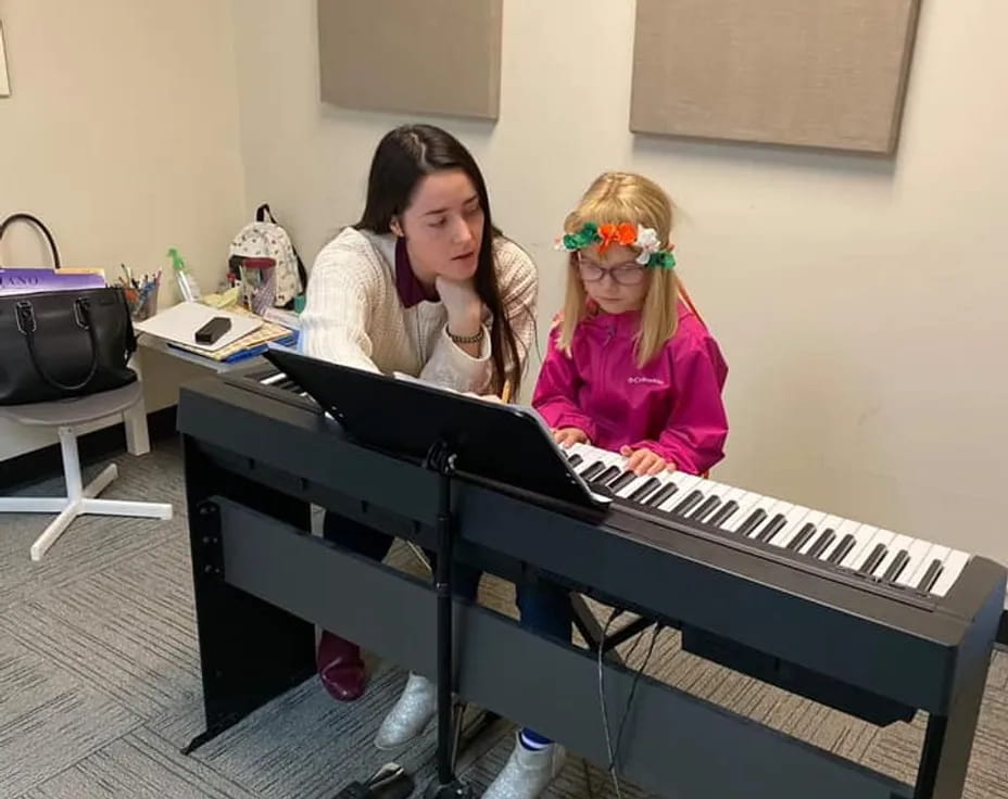 a couple of girls playing a piano