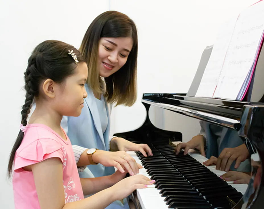 a woman and a girl playing piano
