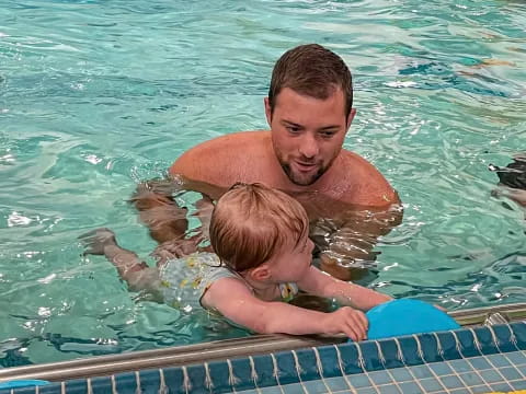 a man holding a baby in a pool