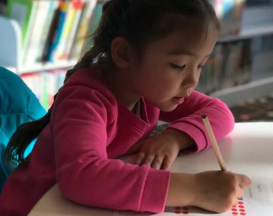 a young girl writing on a book
