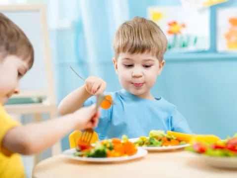 a couple of boys eating at a table