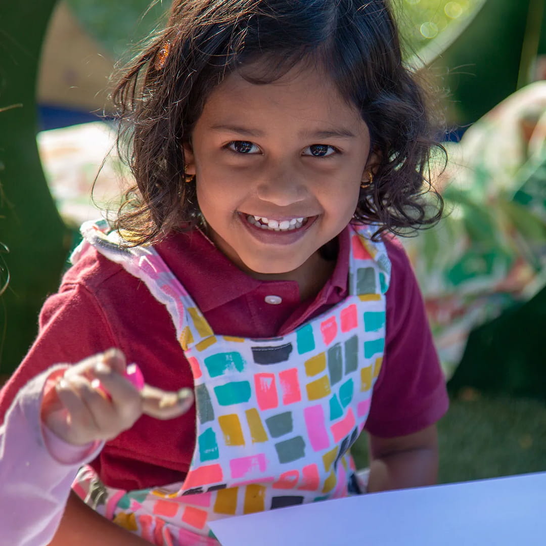 a girl smiling and holding a spoon