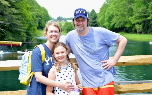 a man and woman with a child by a lake