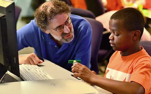 a man and a boy looking at a computer screen