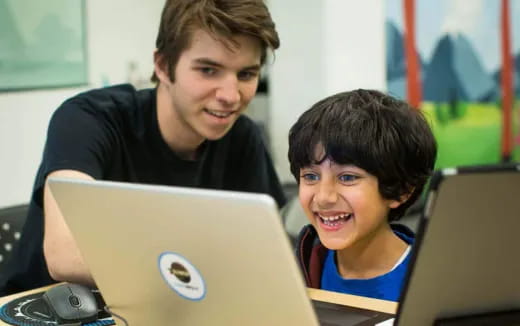 a person and a boy using laptops