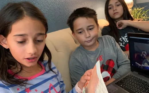 a group of kids looking at a laptop