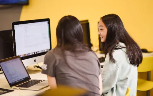 a couple of women looking at a computer screen