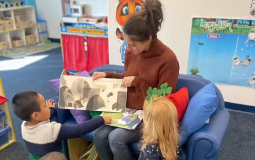 a person reading a book to children