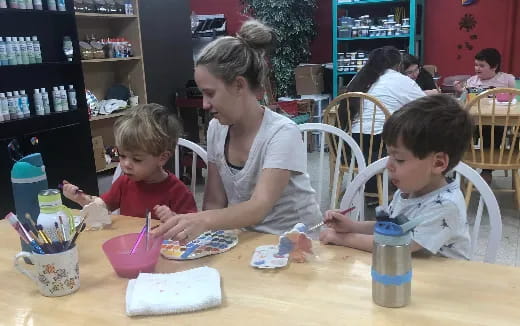 a person and kids sitting at a table with a cake