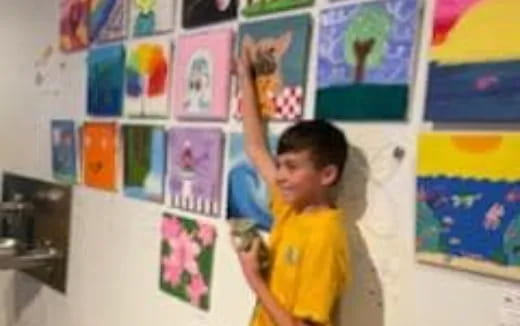 a boy standing in a room with posters on the wall