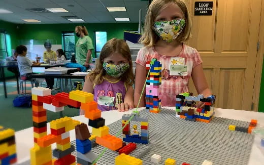 a couple of young girls playing with building blocks