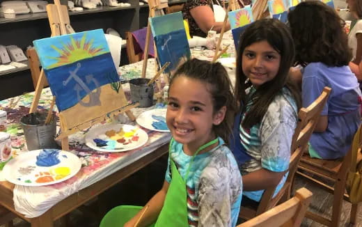 a group of children sitting at a table with food