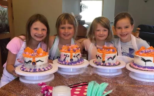 a group of kids sitting at a table with cakes