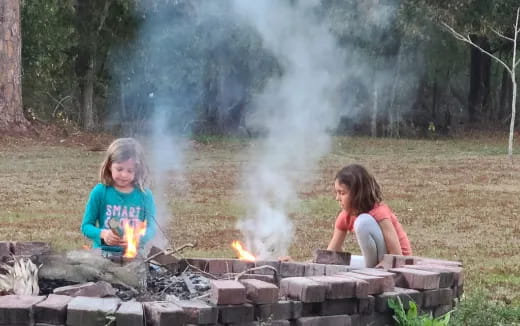 two girls sitting next to a fire