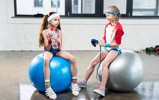 two girls sitting on balls