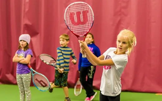 a group of kids holding tennis rackets