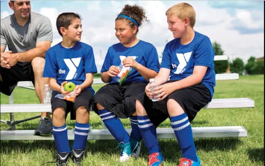 a group of boys sitting on a bench with balls