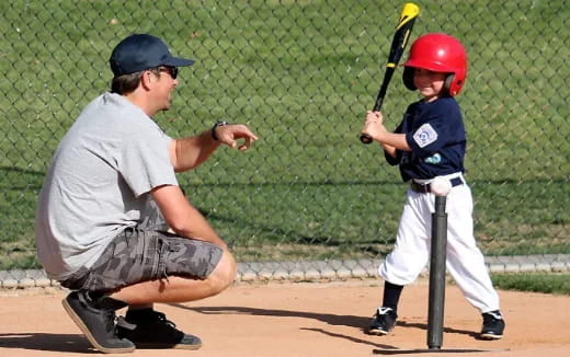 a person and a boy playing baseball