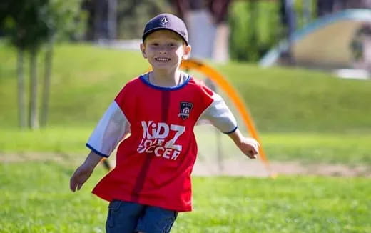 a boy running on a grass field
