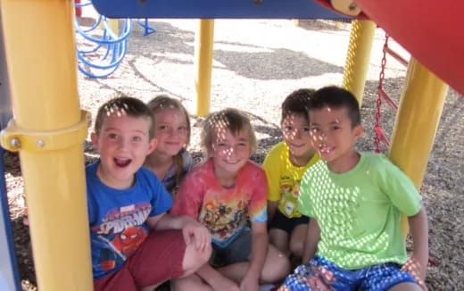 a group of kids sitting on a yellow slide at a beach