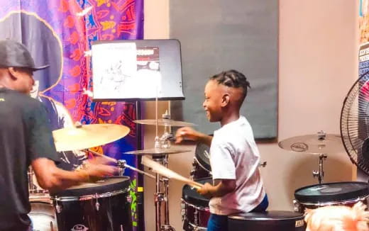 a person playing drums with a boy