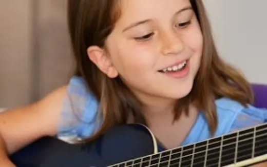 a girl smiling and playing a guitar