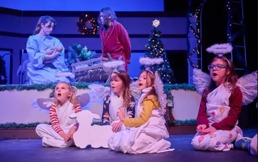 a group of children sitting on a stage