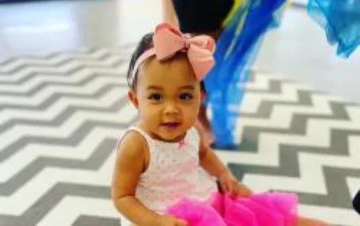 a baby girl wearing a pink dress