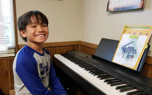 a boy smiling next to a piano