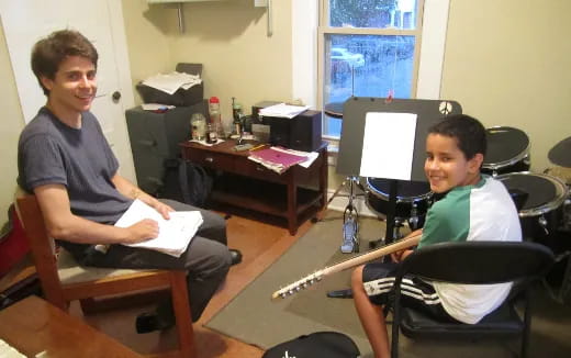 a couple of boys sitting at a desk with a computer