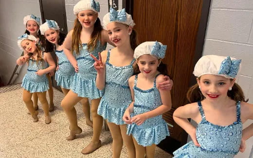 a group of girls wearing blue dresses and hats
