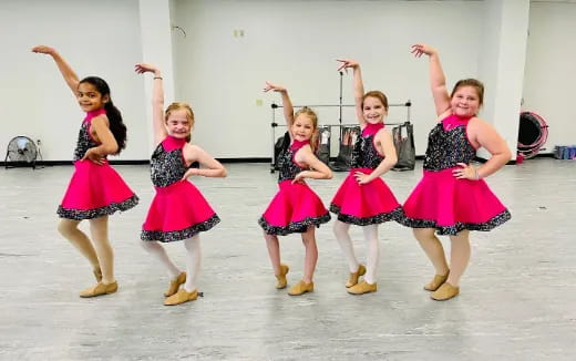 a group of girls in dresses dancing