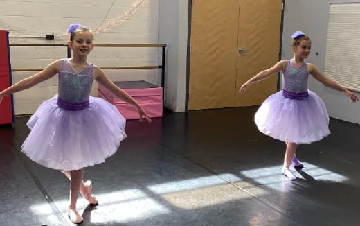 two girls wearing dresses and dancing