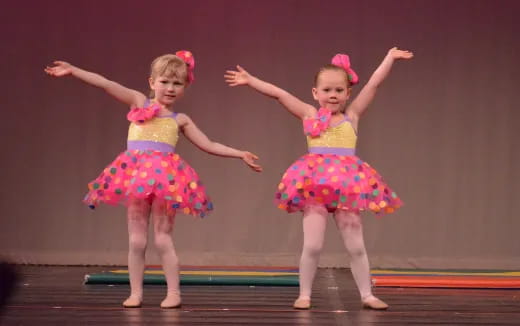 two girls wearing dresses and dancing