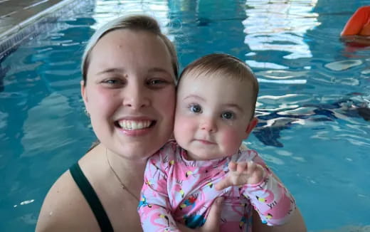 a person holding a baby in a pool