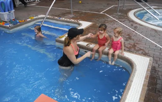 a person and two children in a swimming pool