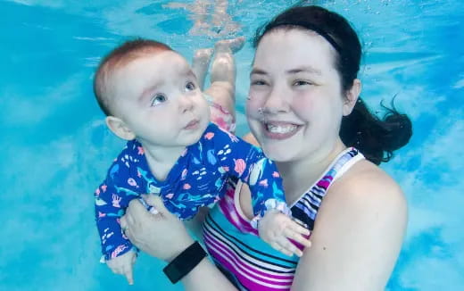 a person holding a baby in a pool