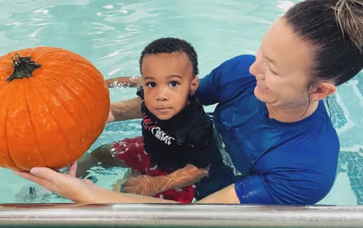 a person and a child in a pool with a ball