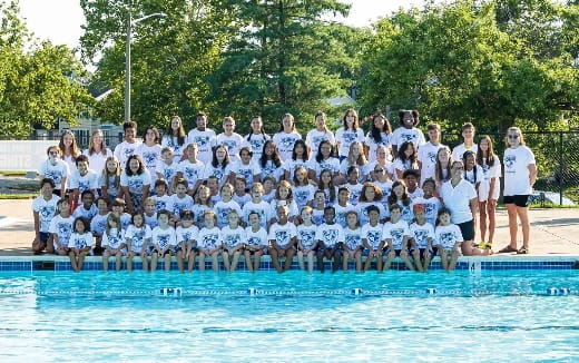 a group of people posing for a photo next to a pool