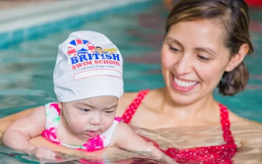 a person holding a baby in a pool