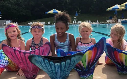 a group of women sitting in chairs by a pool