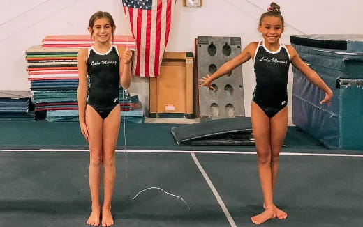a couple of women in leotards on a blue mat