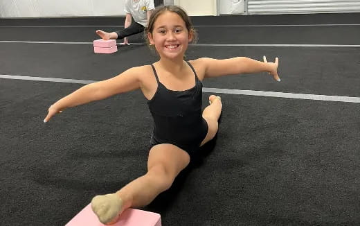 a girl in a leotard doing a handstand on a mat