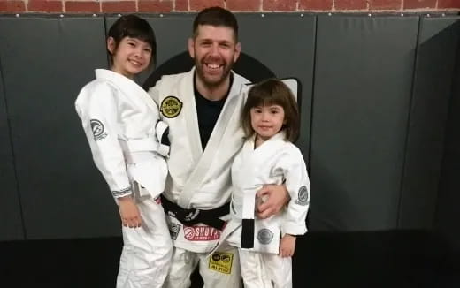a person and two children in karate uniforms